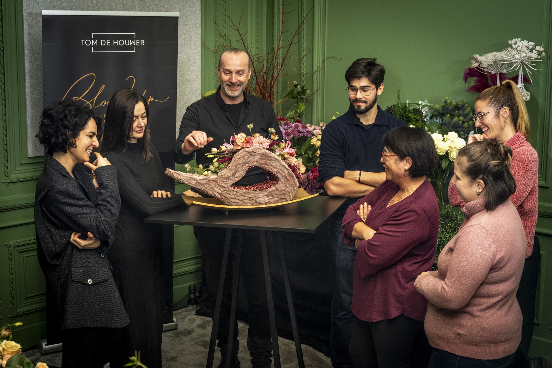 Designer arranging a delicate floral sculpture in a dim atelier